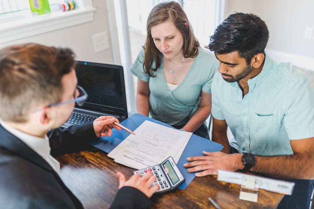 Obtenir un devis Young couple meeting with real estate agent to discuss property purchase.